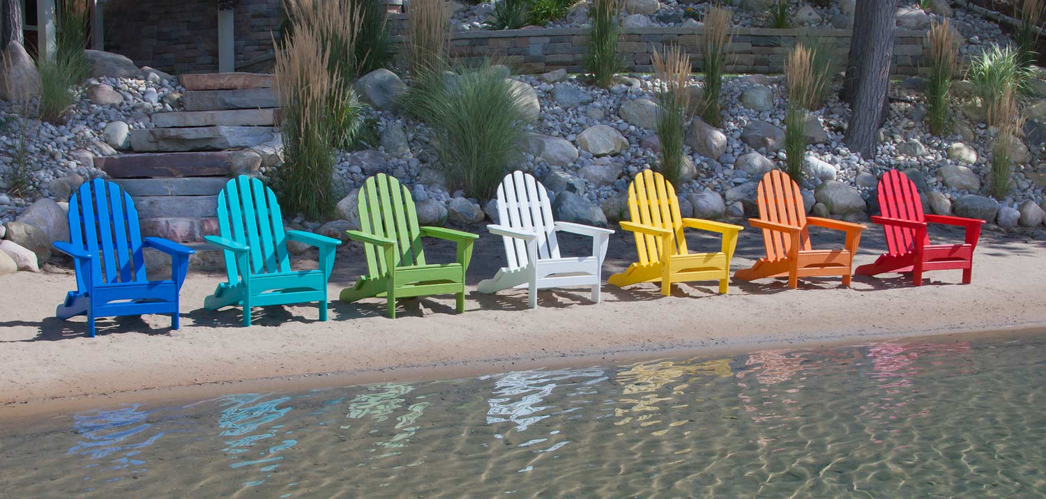 A group of colorful adirondack chairs on a beach.