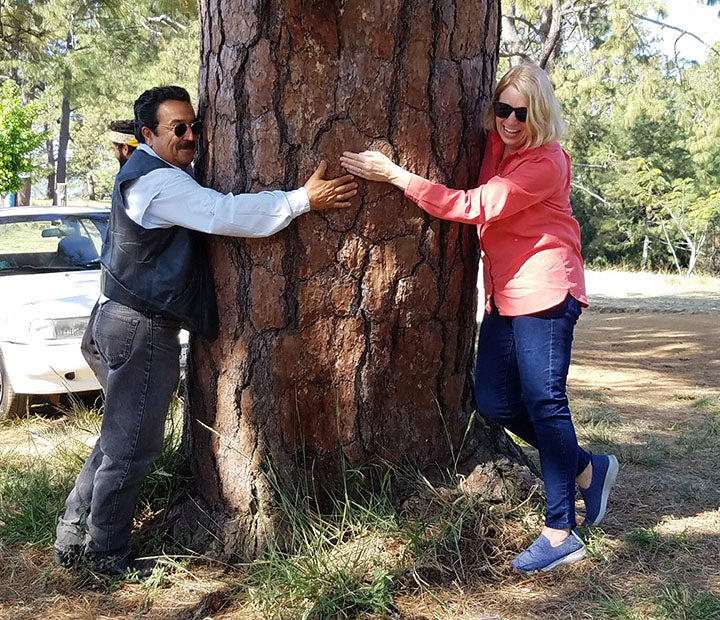 A man and woman hugging a tree.