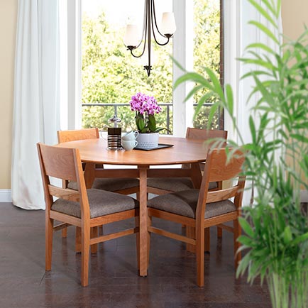 Round wooden dining table with four matching chairs.