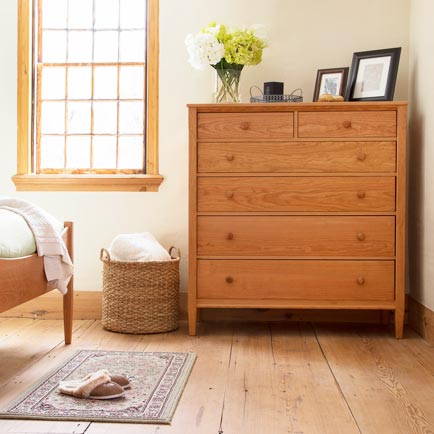 A wooden chest of drawers in a bedroom.