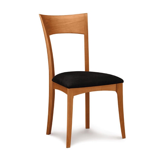 A wooden dining chair with black upholstered seat.