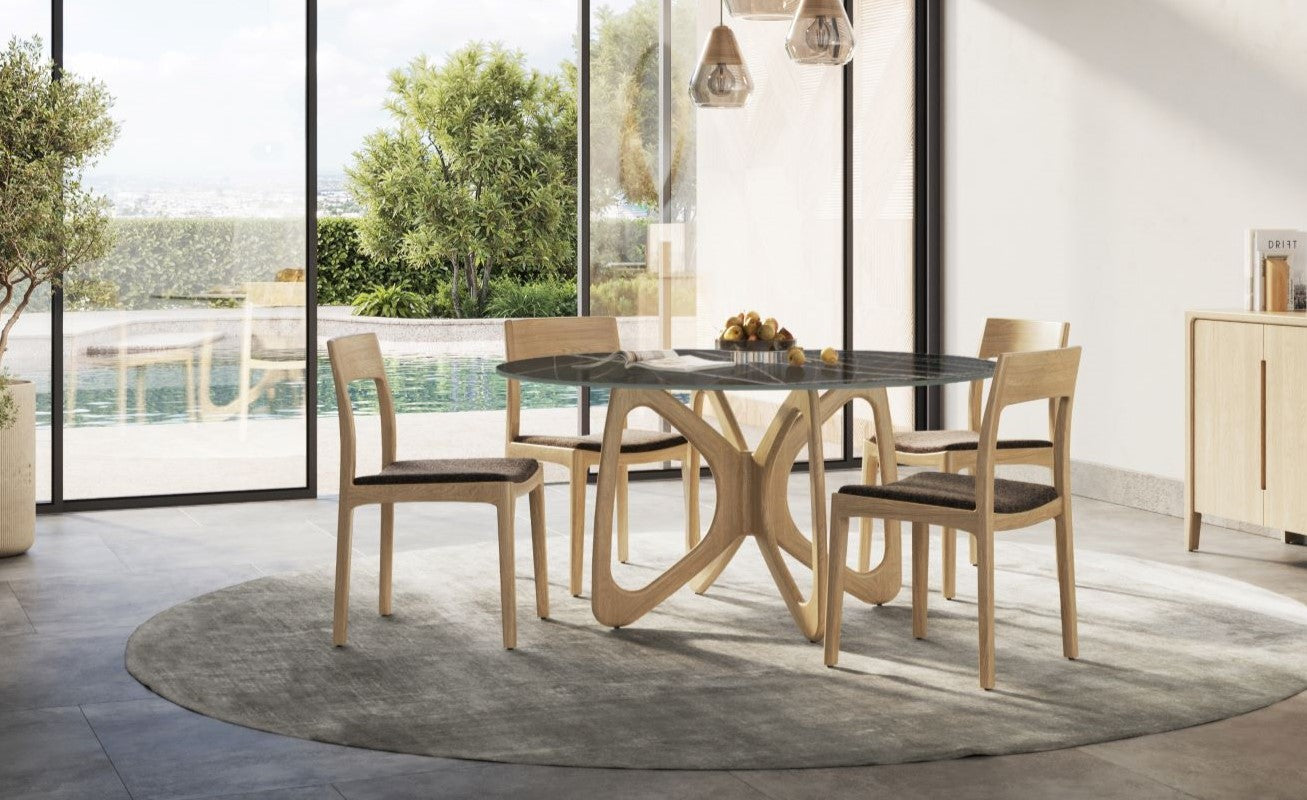 Round glass dining table with wooden chairs on a circular rug.