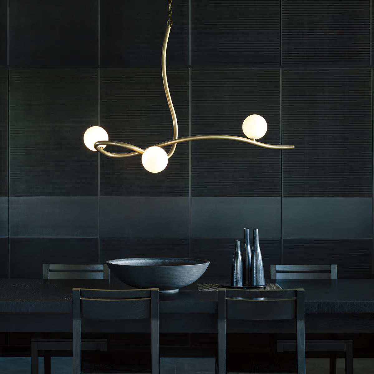 Dark wood dining table is featured beneath the Slide Pendant by Hubbardton Forge, showcasing American craftsmanship and elegant furniture design.