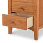 A Maple Corner Woodworks American Shaker 3-Drawer Nightstand crafted with eco-friendly materials features three drawers, one partially open, revealing a light-colored interior. The nightstand showcases a round wooden knob influenced by Vermont craftsmanship and is set against a white background.
