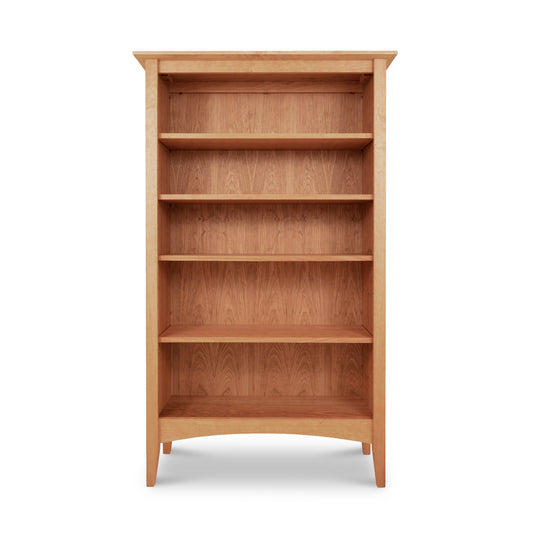 A solid wood American Shaker Bookcase featuring four evenly spaced shelves. Crafted from sustainably harvested hardwoods, this natural cherry bookshelf from Maple Corner Woodworks showcases a light brown finish with a simple, sturdy design. The bookcase includes a small gap underneath the bottom shelf, and the back and sides match the shelves in both color and material. Ideal for those seeking high-quality Vermont-made or cherry wood furniture.
