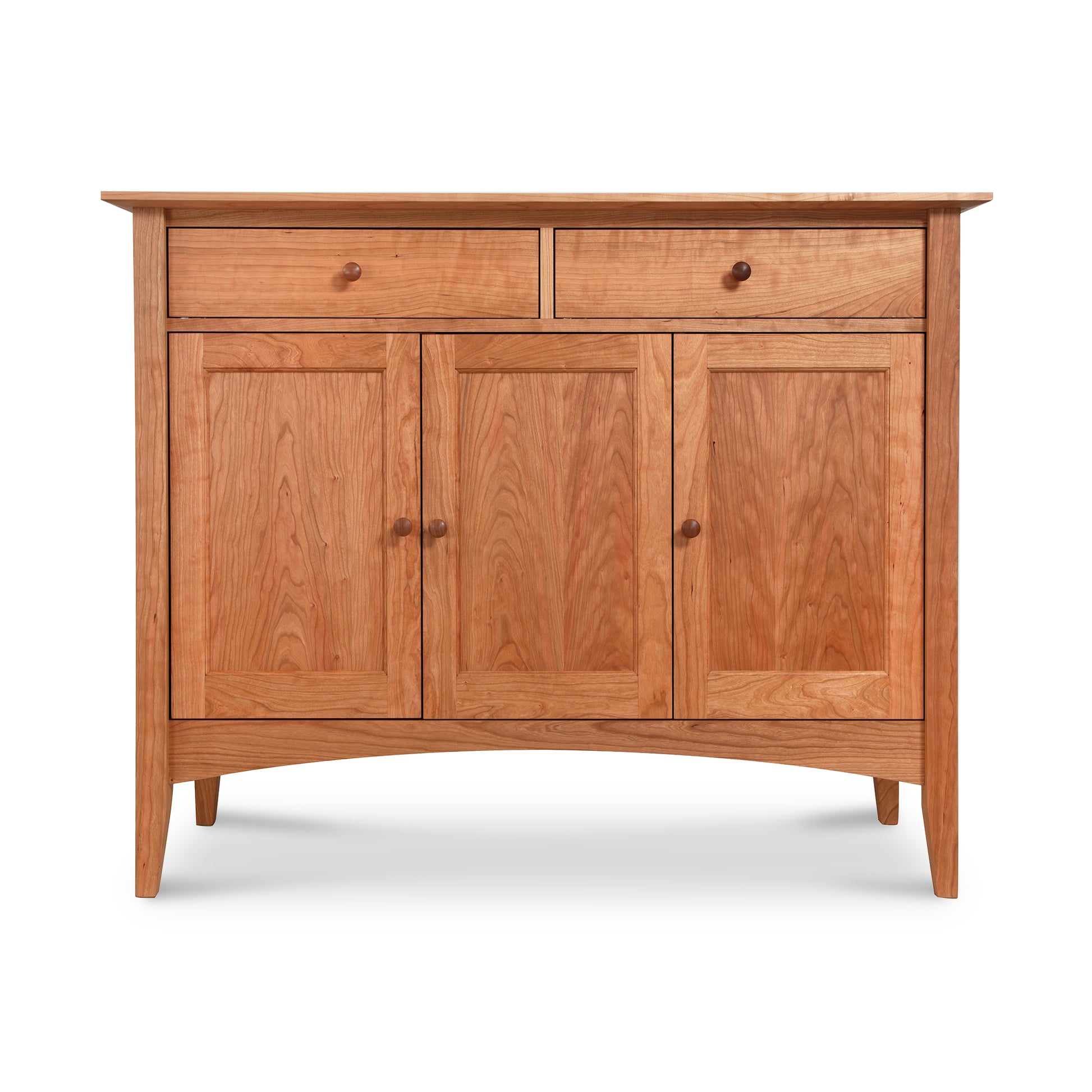 The American Shaker Medium Sideboard by Maple Corner Woodworks is a beautifully crafted piece made from solid hardwood. It includes two upper drawers and three lower cabinet doors, all in a natural wood finish with simple round knobs that showcase the quality of Vermont craftsmanship. This sideboard stands elegantly on four tapered legs.