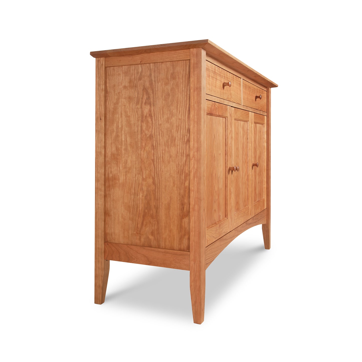 The American Shaker Medium Sideboard by Maple Corner Woodworks showcases a simple and classic design rooted in American Shaker style. Made in Vermont from solid hardwood, this sideboard includes two drawers and cabinet doors adorned with small round knobs. The light brown wood has a smooth finish and stands elegantly on four tapered legs.