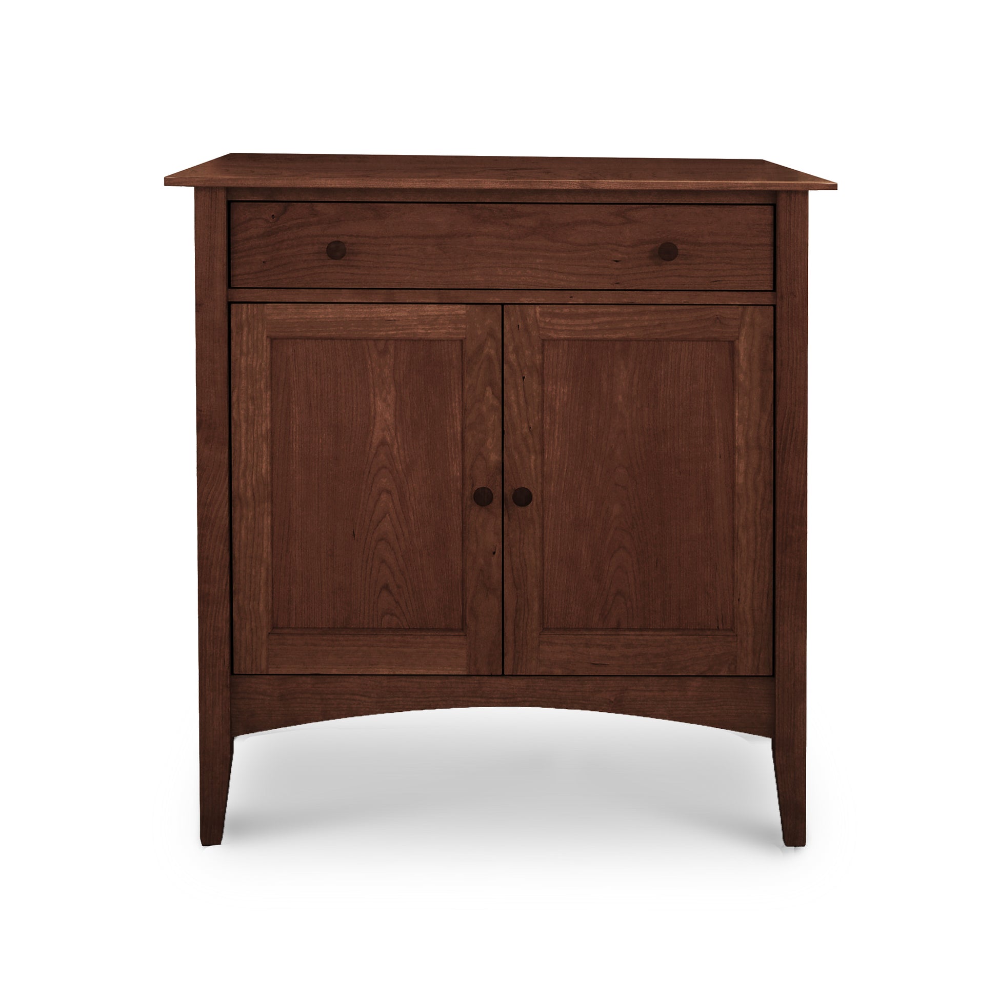 The American Shaker Small Sideboard by Maple Corner Woodworks is crafted from solid hardwood in Vermont and showcases a dark brown finish. Drawing inspiration from the American Shaker style, this piece features simple lines with a single drawer on top and two doors below, elegantly adorned with round knobs and supported by four tapered legs.