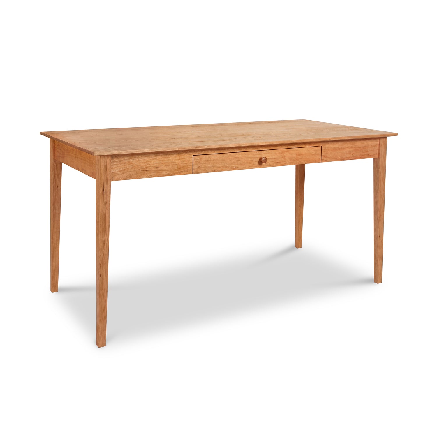 The American Shaker Writing Desk by Maple Corner Woodworks showcases a minimalist design with a central drawer. Expertly crafted by Vermont artisans using sustainably sourced hardwood, it features a light brown finish and is supported by four straight legs.