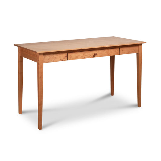 An American Shaker Writing Desk - Floor Model with a simple, minimalist design featuring a flat rectangular surface and four straight legs. It has a natural cherry finish, reminiscent of Vermont craftsmanship, and a single drawer integrated into the front for storage. The desk stands on a white background from Maple Corner Woodworks.