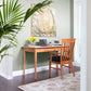 Handcrafted wooden desk showcasing laptop, books, and yellow flowers, accompanied by Vermont Woods Studios' elegant Country Shaker Chair.