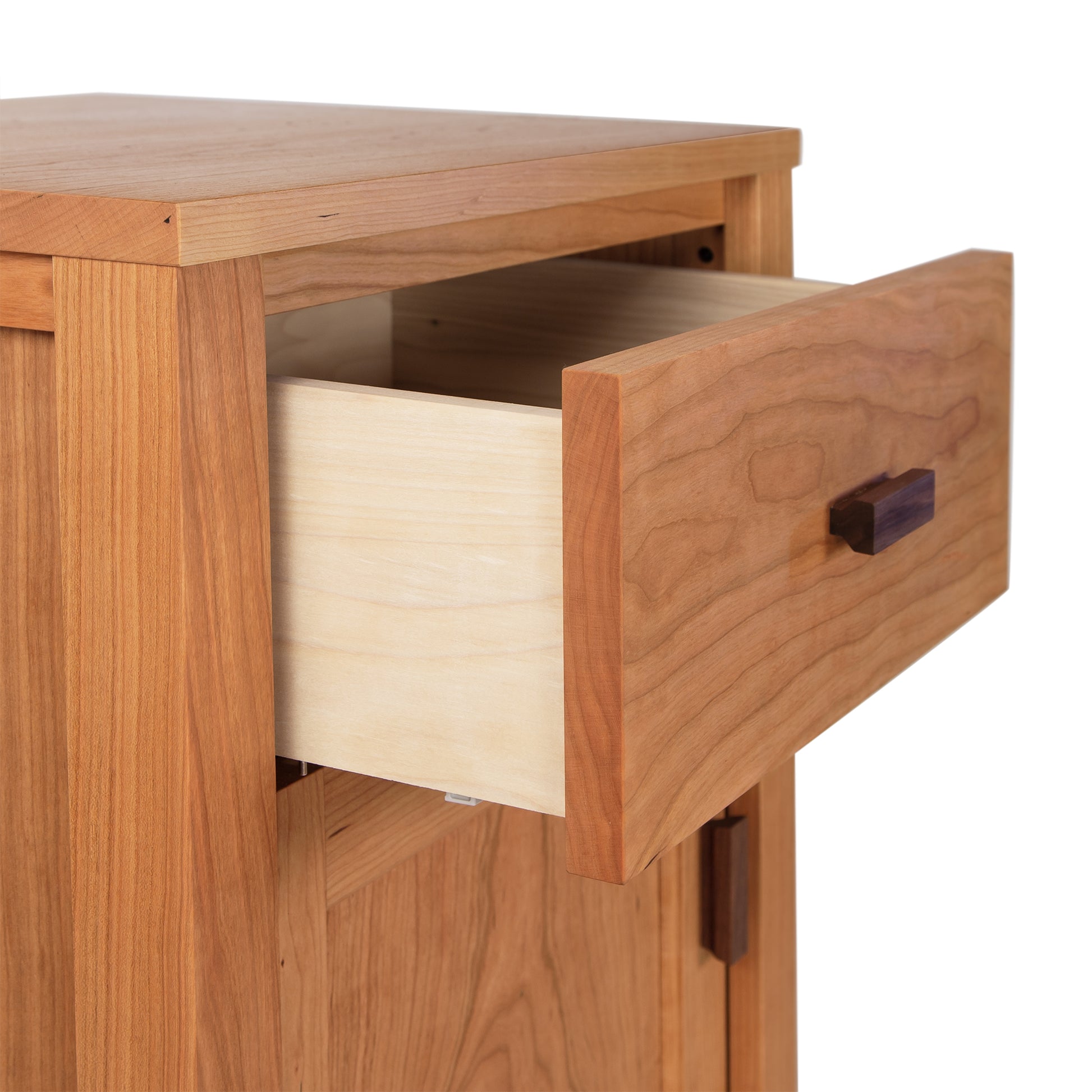 A close-up of a partially open drawer in a Maple Corner Woodworks Andover Modern 1-Drawer Nightstand with Door, showing the grain and detail of the sustainable hardwoods on both the drawer and the nightstand. The drawer pull is a...