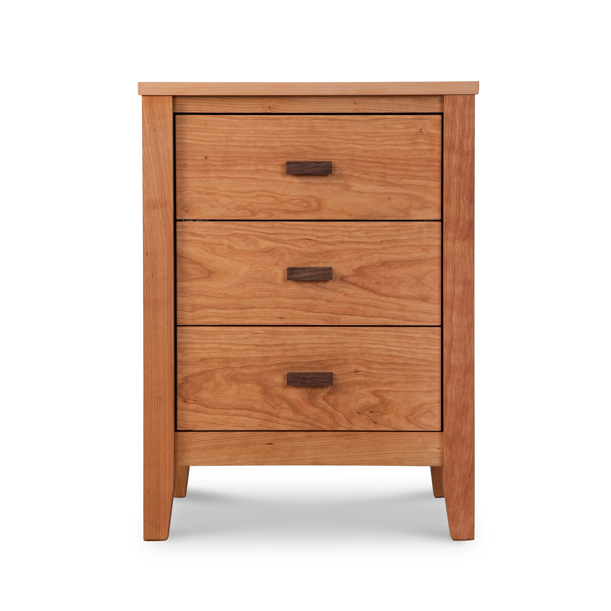 A Maple Corner Woodworks Andover Modern 3-Drawer Nightstand with simple, rectangular pulls on a plain white background. The nightstand features a subtle overhang on the top and understated side paneling. It is designed as eco-friendly.