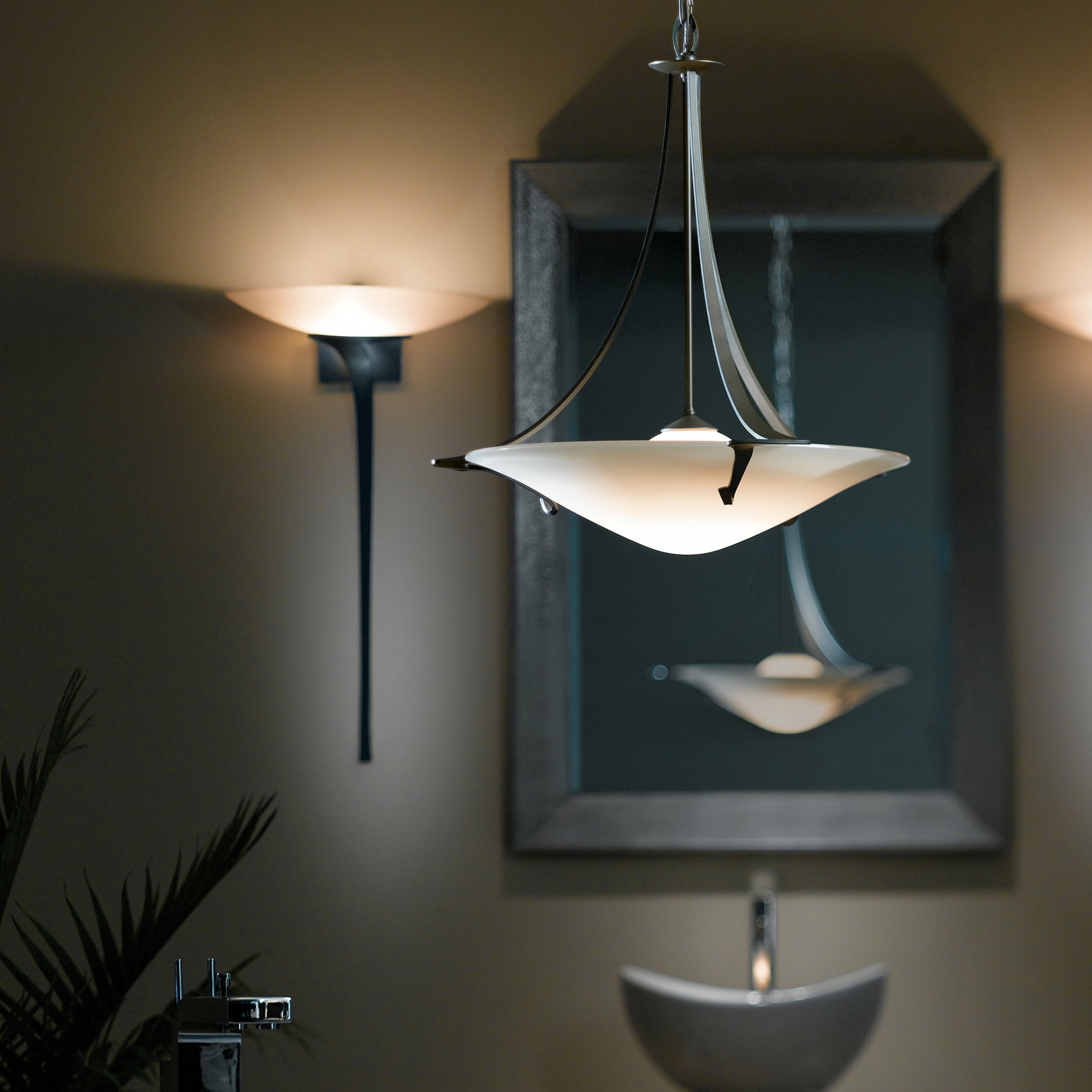 An elegant bathroom with a sink, mirror, and the Hubbardton Forge Antasia Pendant showcasing exquisite craftsmanship.