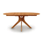An Audrey Round Extension Dining Table by Copeland Furniture, a solid wood oval dining table with three legs.