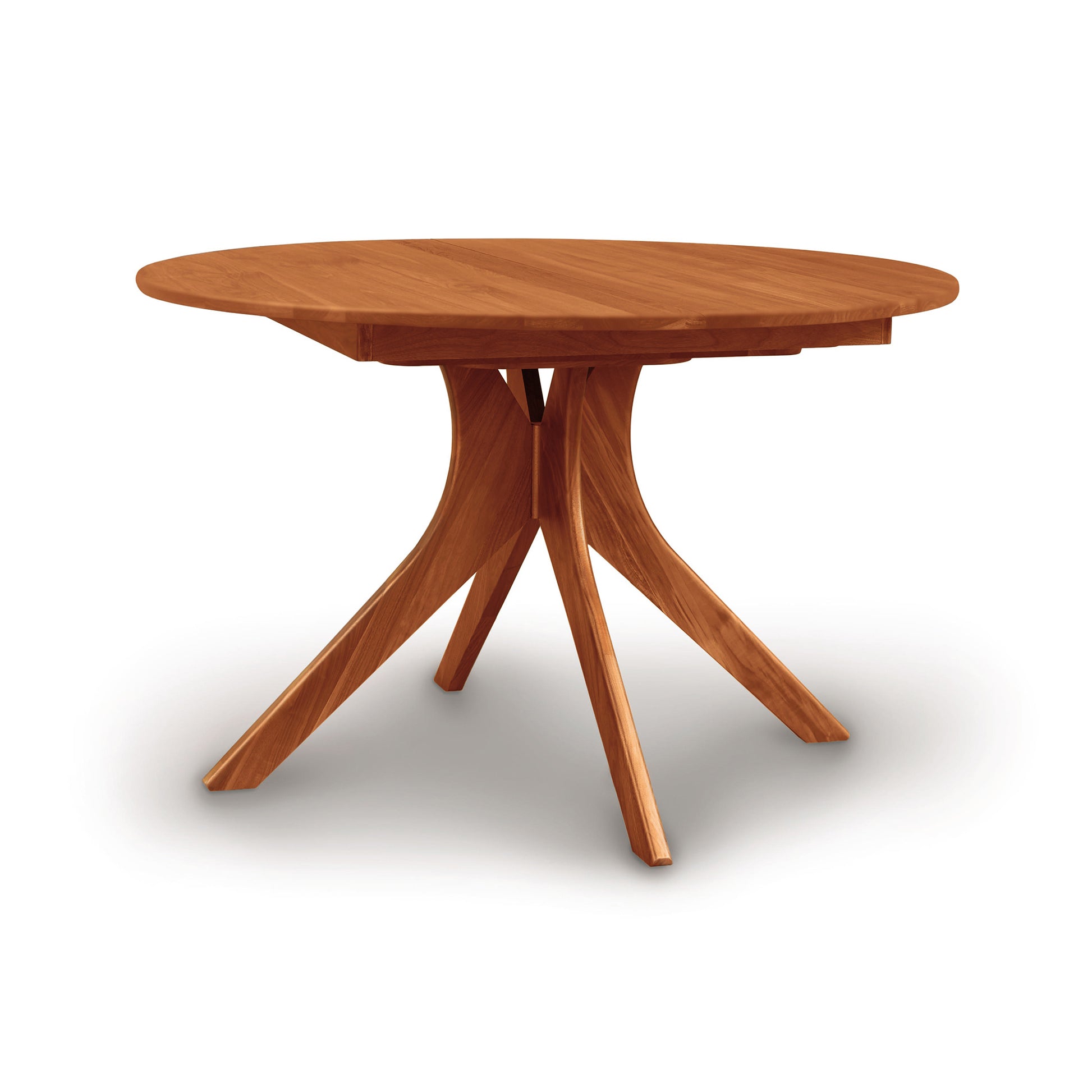A solid wood Copeland Furniture Audrey Round Extension Dining Table with a round top and a unique star-shaped base, isolated on a white background.