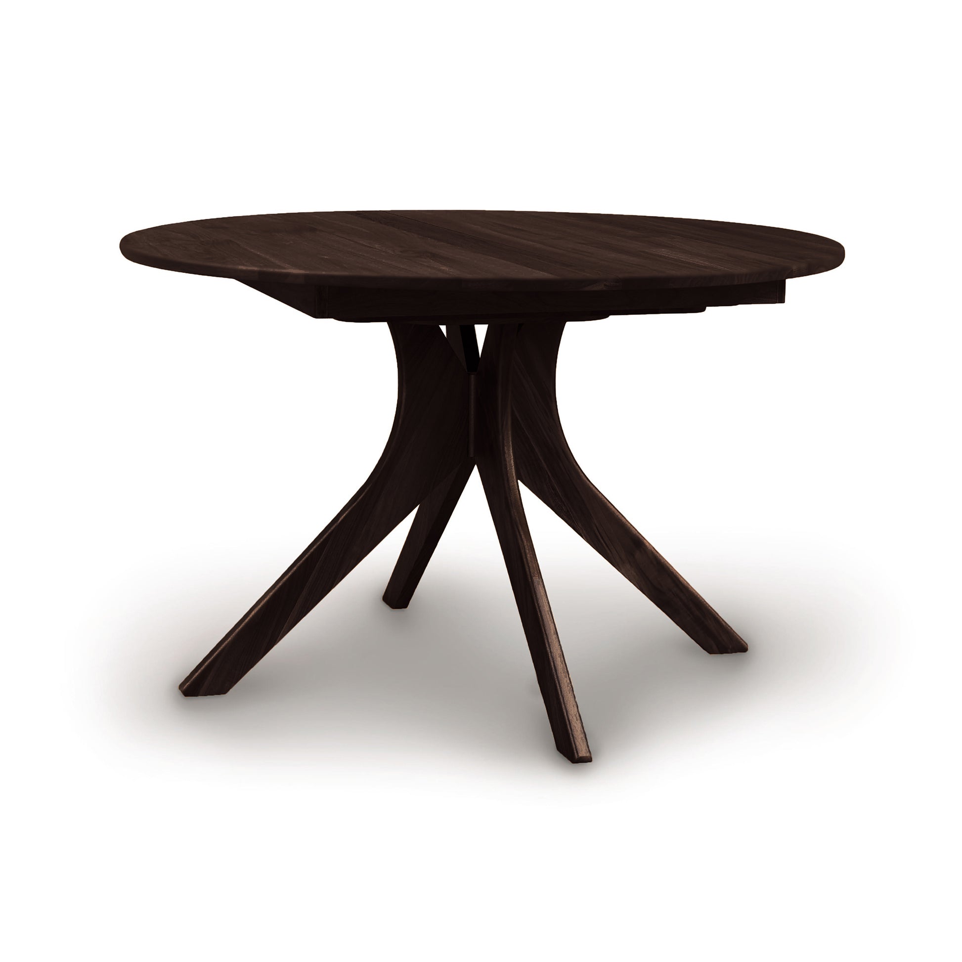 A round, dark solid wood Audrey Round Extension Dining Table with a unique pedestal base and a butterfly leaf mechanism, isolated on a white background by Copeland Furniture.