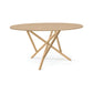 Baton Round Solid Top Dining Table by Copeland Furniture with a flat surface and angled intersecting legs, showcasing modern American craftsmanship.