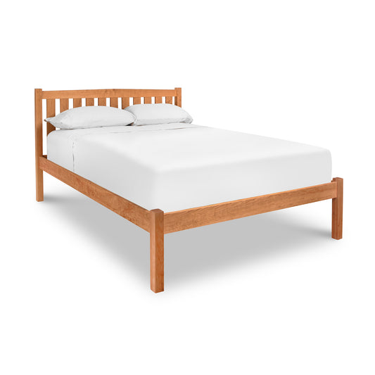 A customizable Bennington Bed with Low Footboard by Vermont Furniture Designs with white sheets on it.