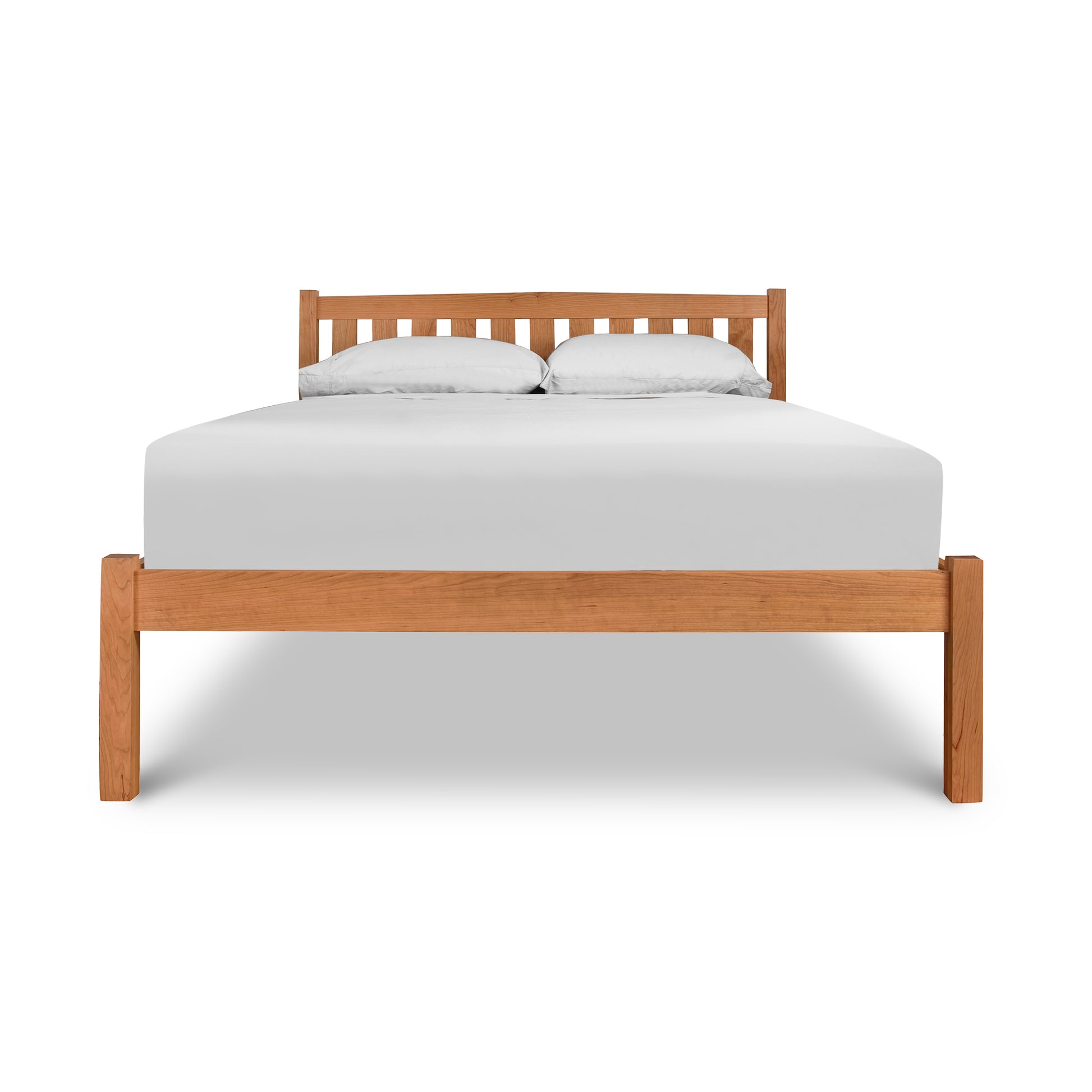 A Vermont Furniture Designs Bennington Bed with Low Footboard in cherry walnut wood, paired with a white mattress and two pillows against a white background.