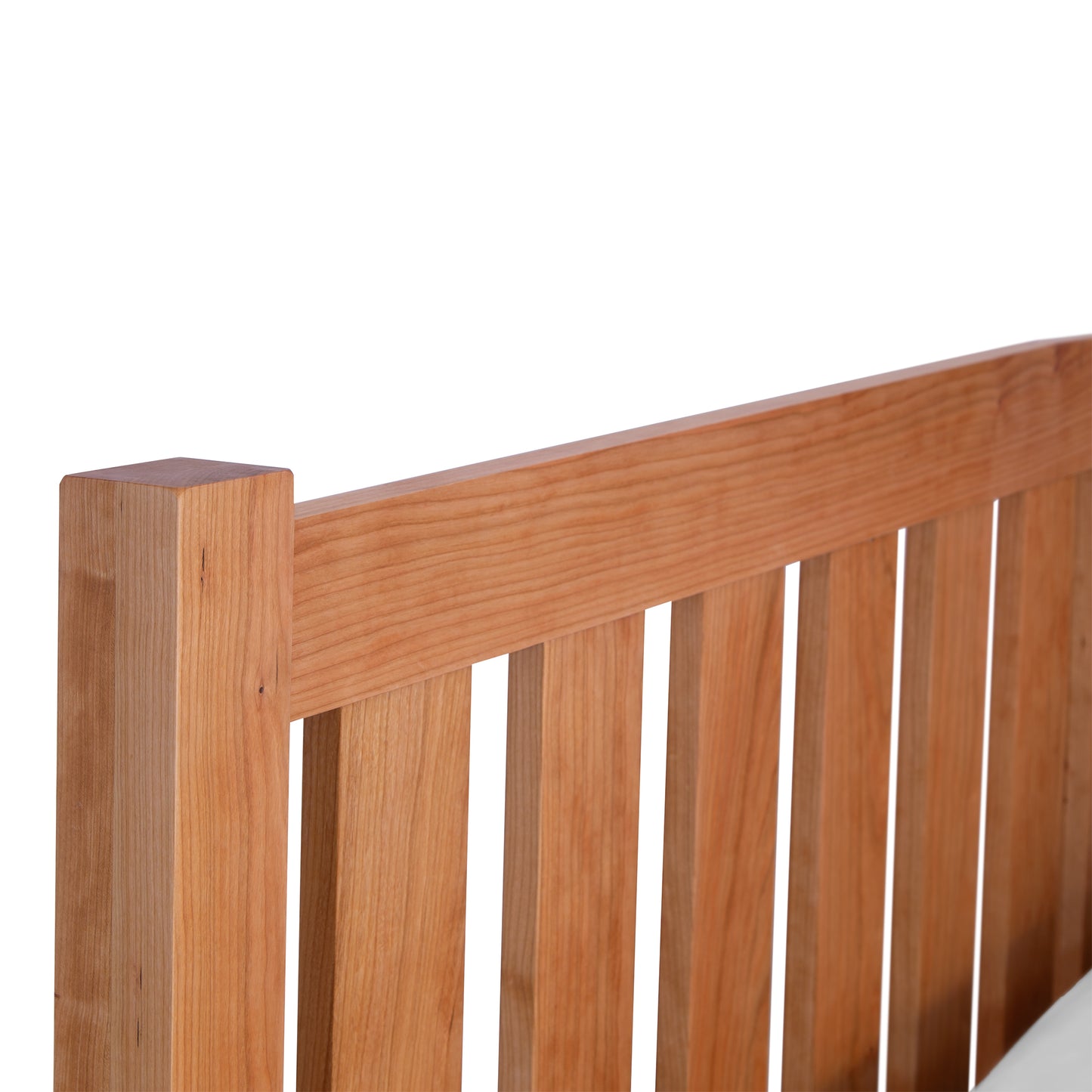 Part of a Vermont Furniture Designs Bennington Bed with Low Footboard, made of cherry walnut wood slats, isolated on a white background.