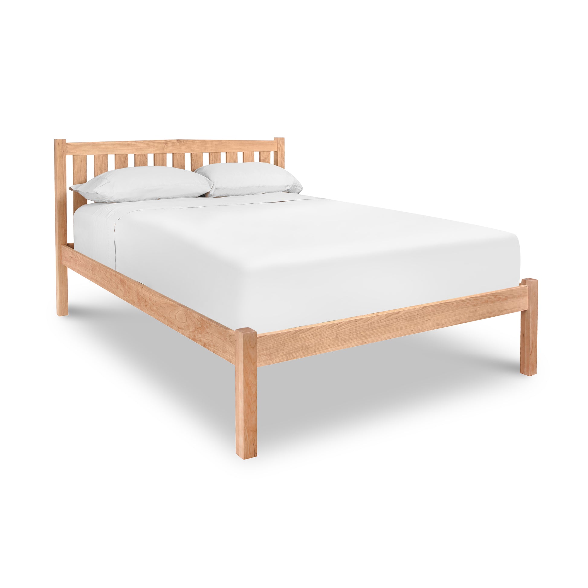 A Bennington Bed with Low Footboard in cherry walnut wood with a white mattress and two pillows against a white background features the Vermont Furniture Designs Bennington Low Footboard.