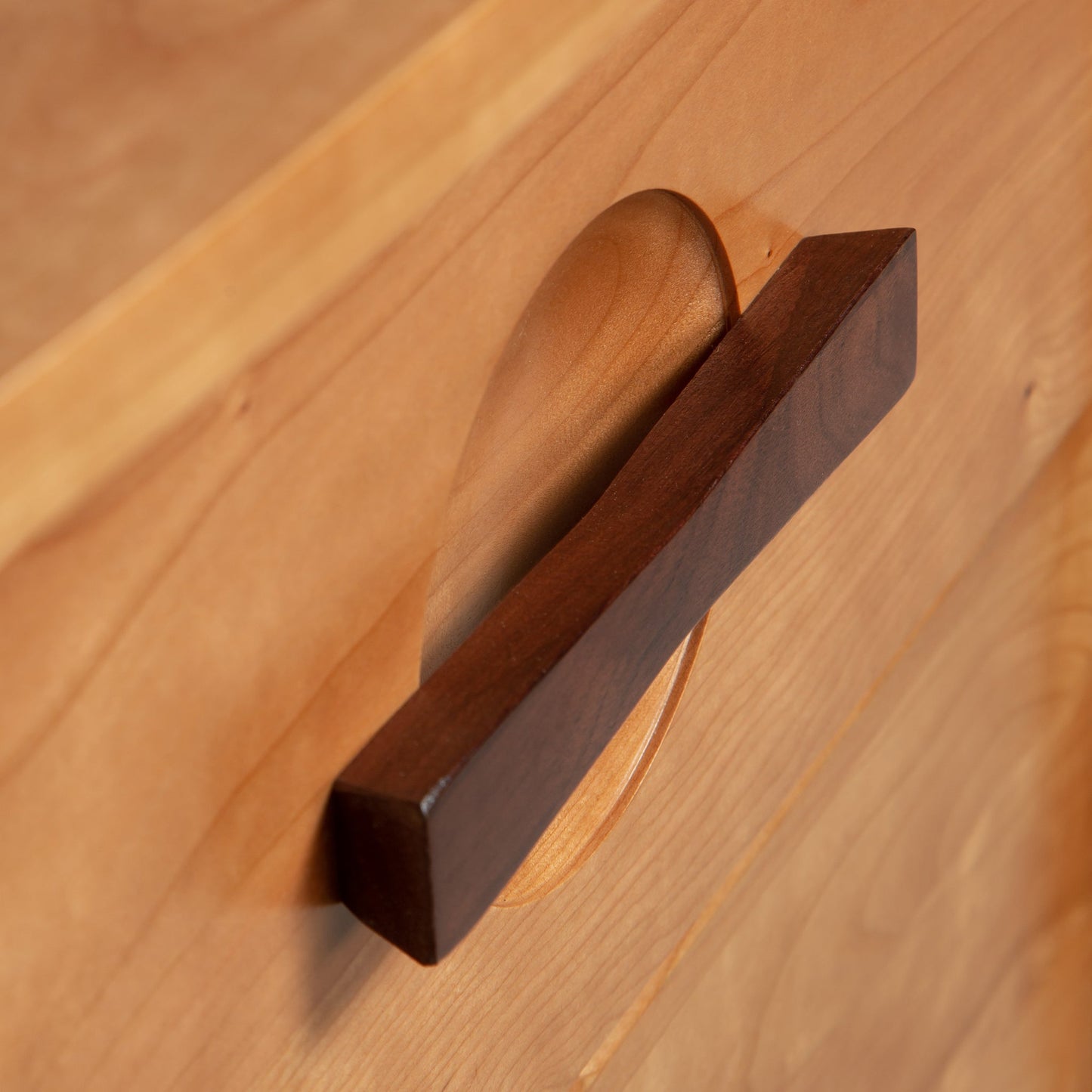 A close up of a wooden drawer handle.
