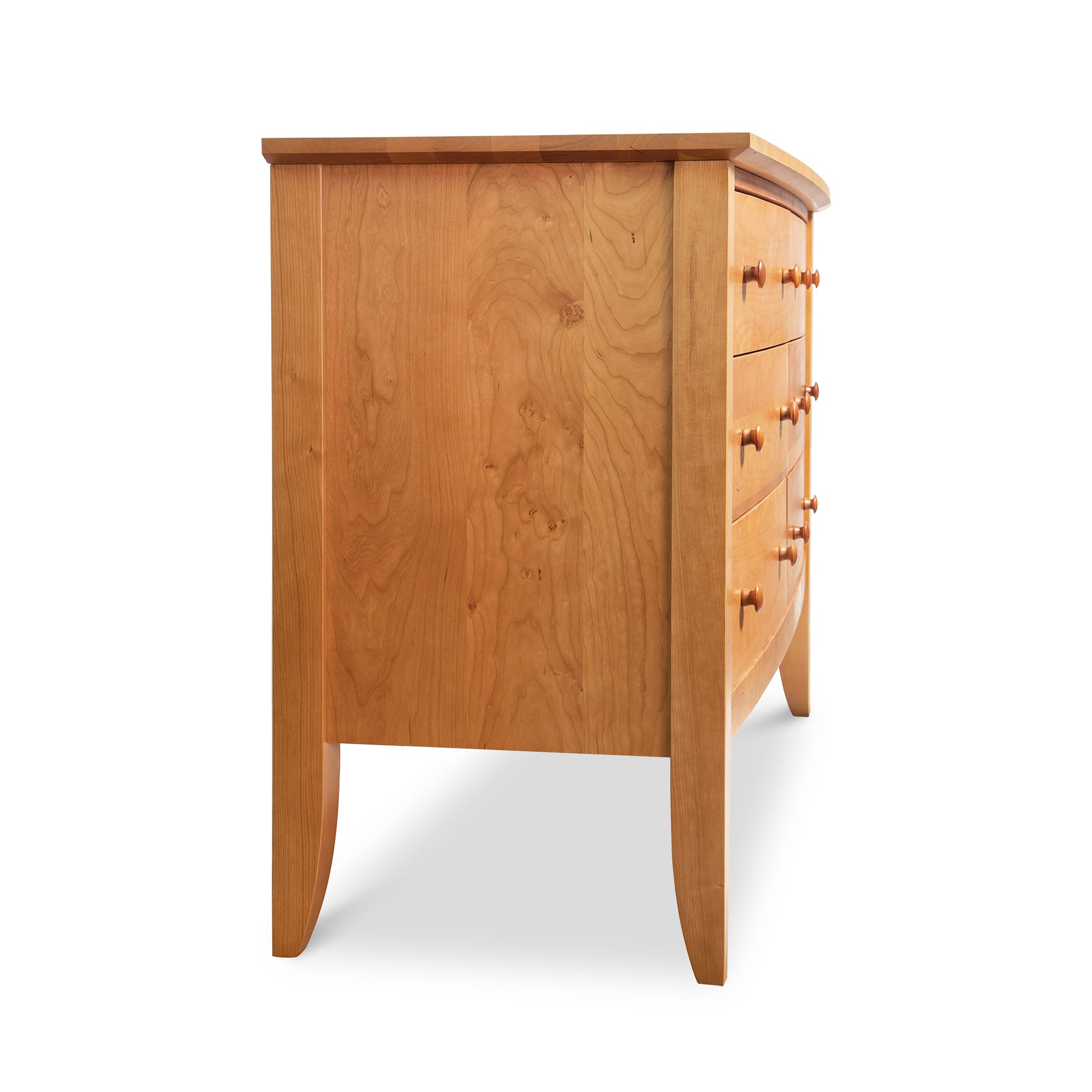 Side view of the Bow Front 6-Drawer Dresser by Lyndon Furniture, handcrafted in Vermont from solid wood with a natural finish. This American-made double dresser features a distinctive bow front design and six drawers, each with round knobs. Curved legs enhance the elegant style of this Vermont-made furniture piece. Shown against a white background.