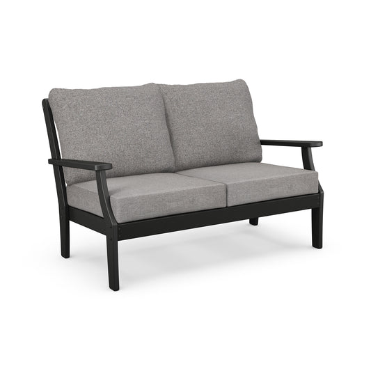 A modern two-seater sofa with a black metal frame and light gray cushions, made from recycled plastic lumber, isolated on a white background. (POLYWOOD Braxton Deep Seating Settee)