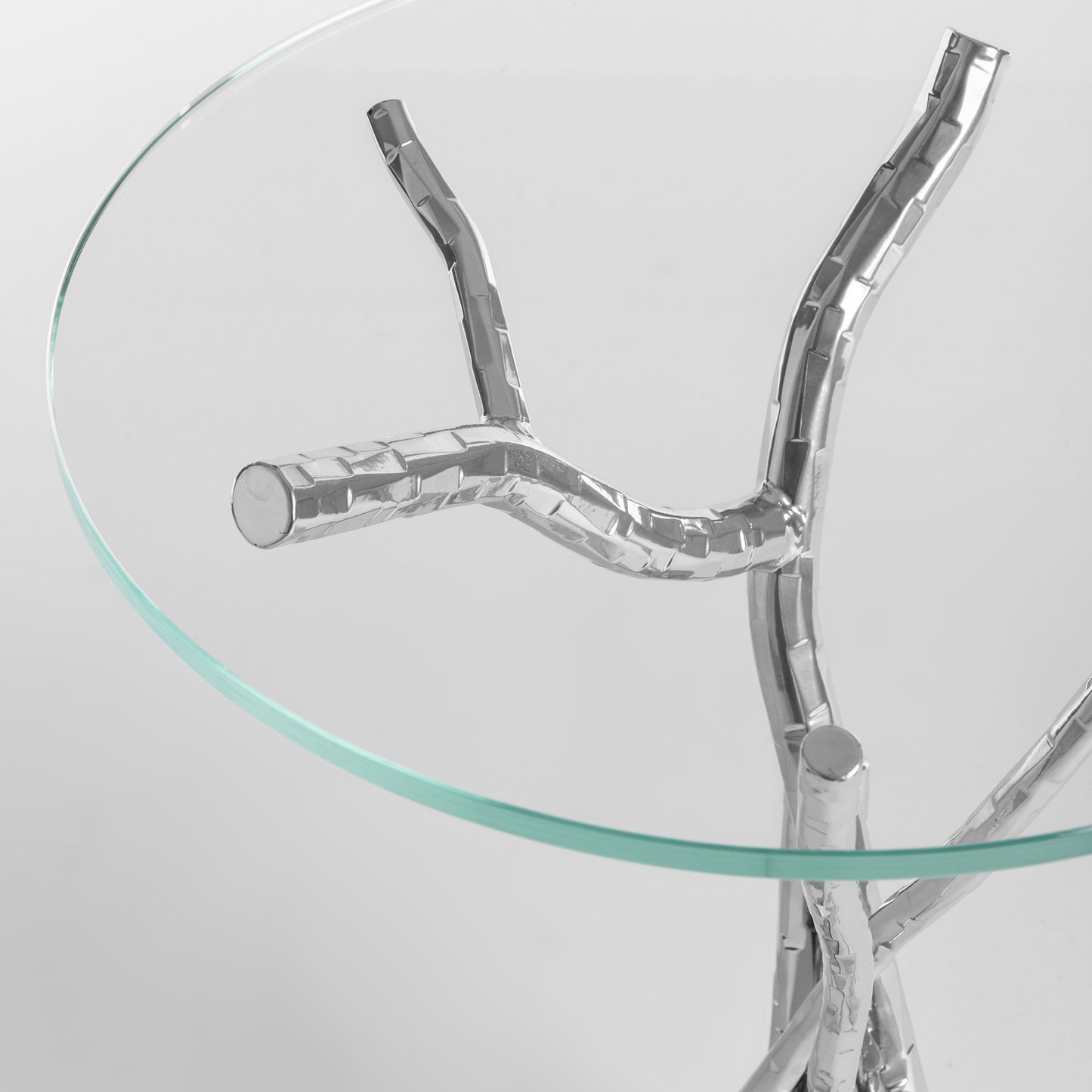 A Brindille Accent Table by Hubbardton Forge, with branches on it, featuring a hand-hammered steel base.