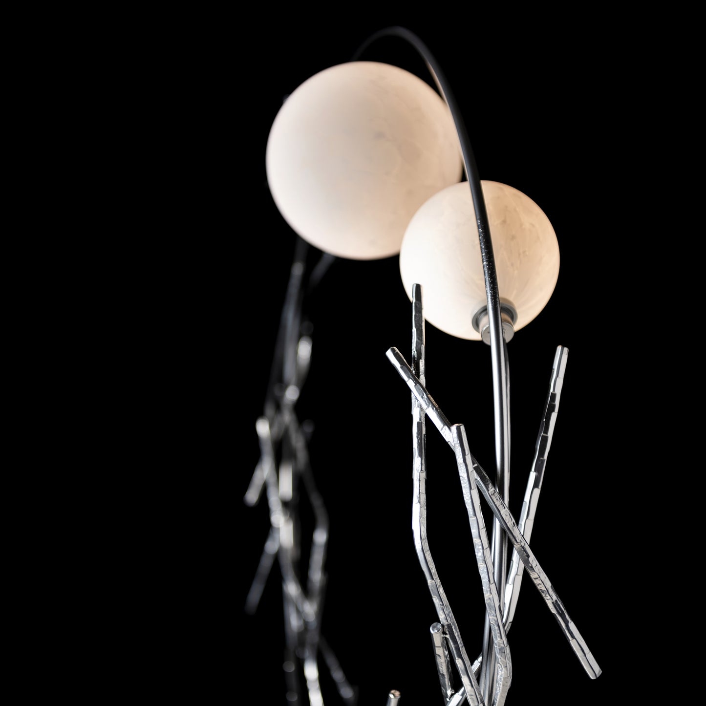 The Brindille Ring Lamp by Hubbardton Forge showcases elegant white shades and silver rods, highlighting fine American craftsmanship.