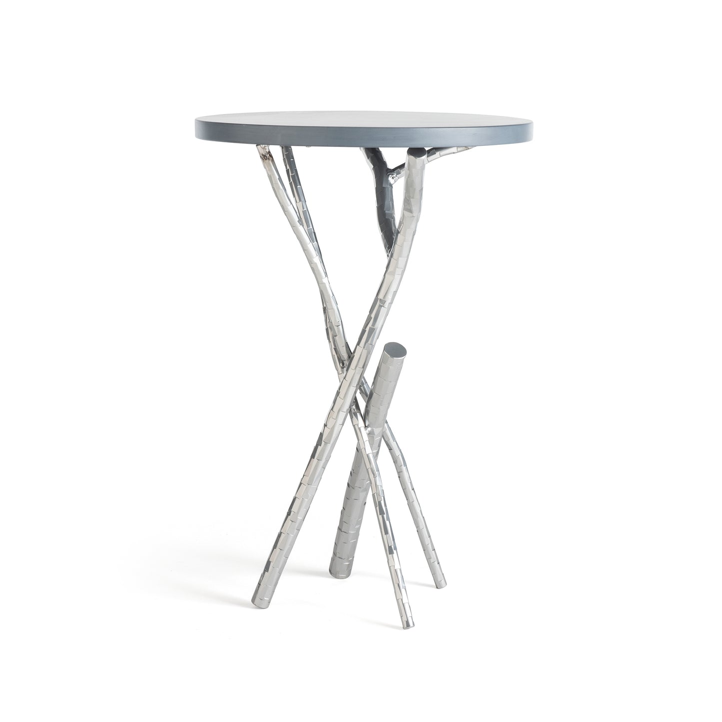 The Brindille Wood Top Accent Table by Hubbardton Forge is a distinctive piece featuring a smooth, gray tabletop. Its handcrafted base showcases an artistic design of three intertwined silver metallic branches, echoing the elegance of Vermont maple craftsmanship as it stands gracefully against a white background.