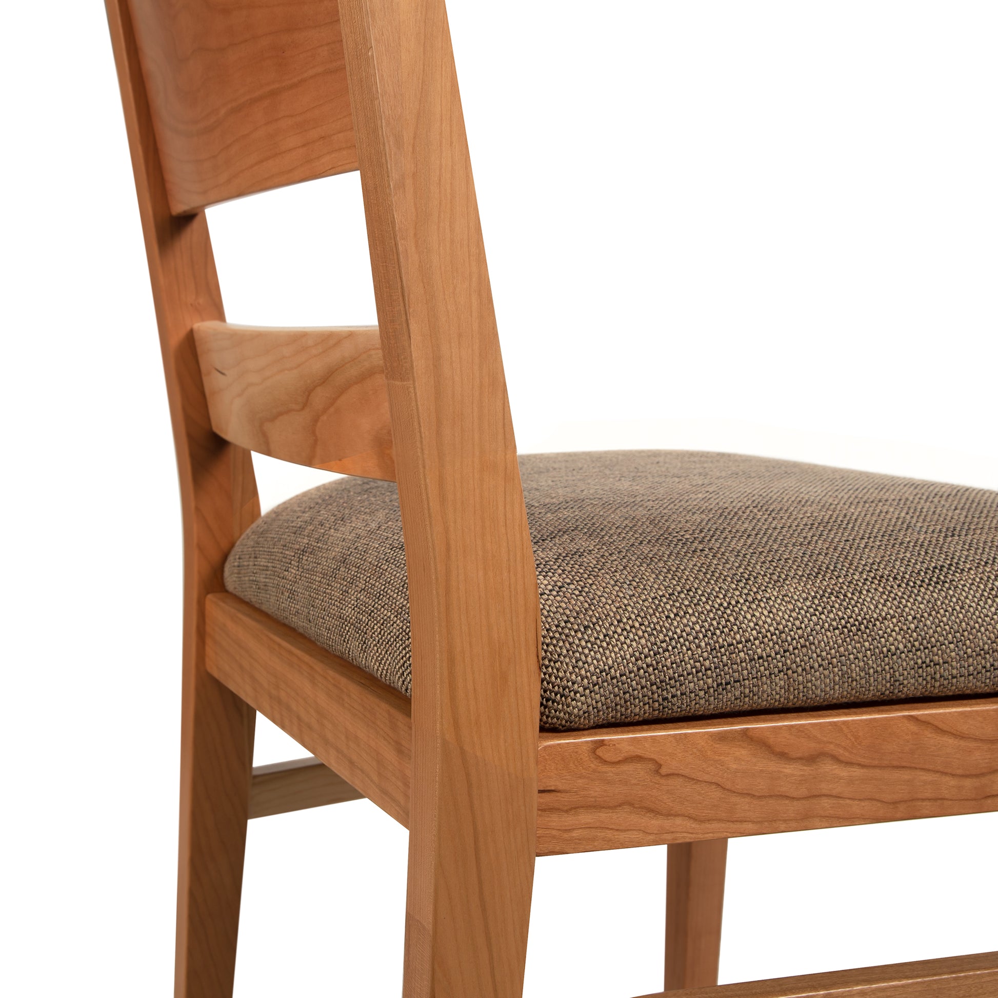 A wooden chair with a tan upholstered seat.