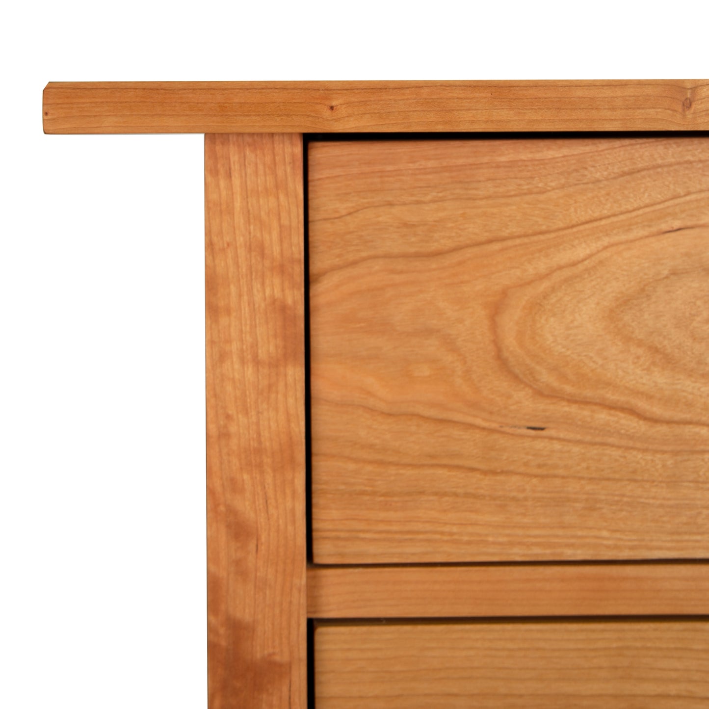 A close-up of a corner of a Burlington Shaker 6-Drawer Chest by Vermont Furniture Designs showing the tabletop and the patterns of the wood grain.