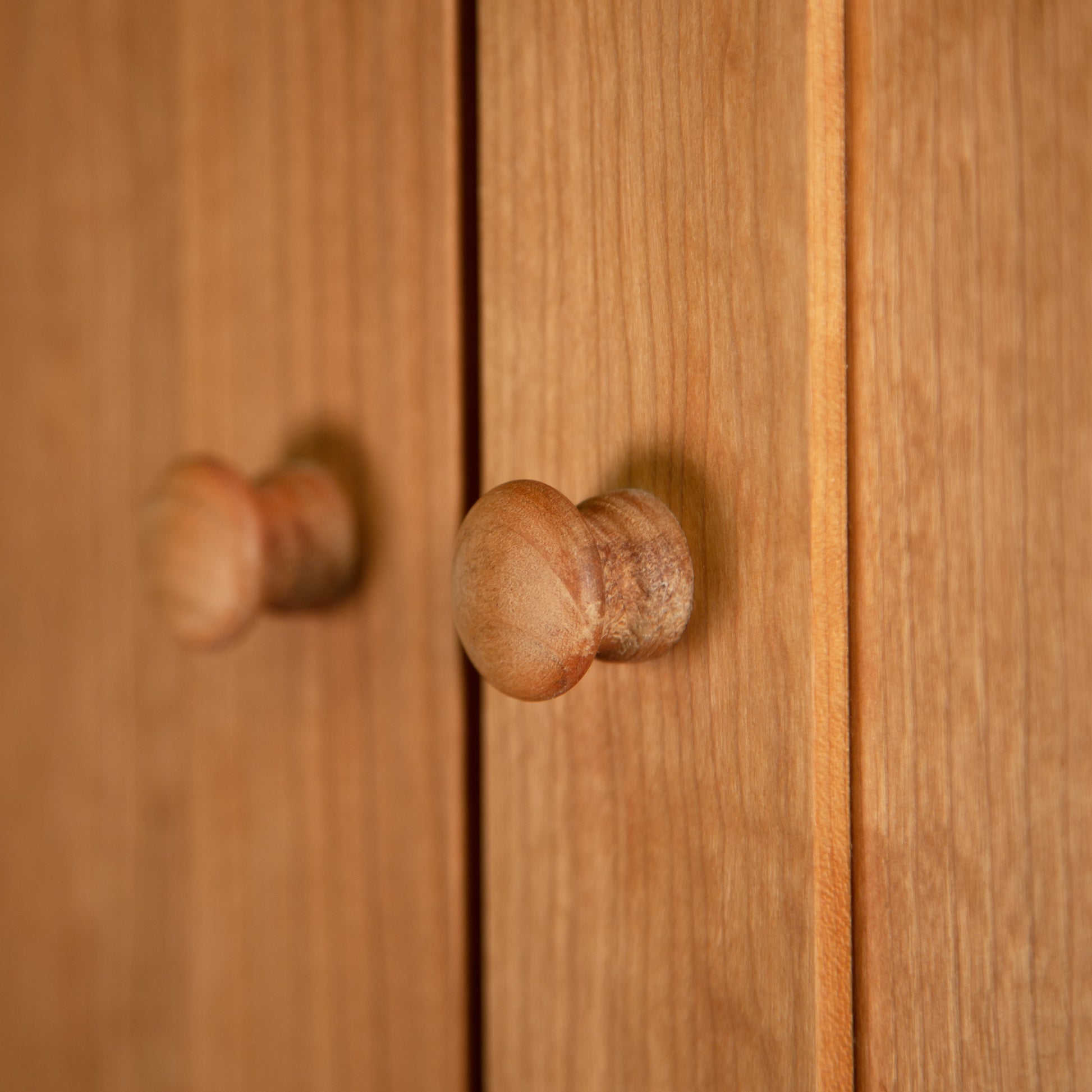 A close up of a solid wood Burlington Shaker Tall Storage Chest with wooden knobs, showcasing the Vermont Furniture Designs Shaker Style.