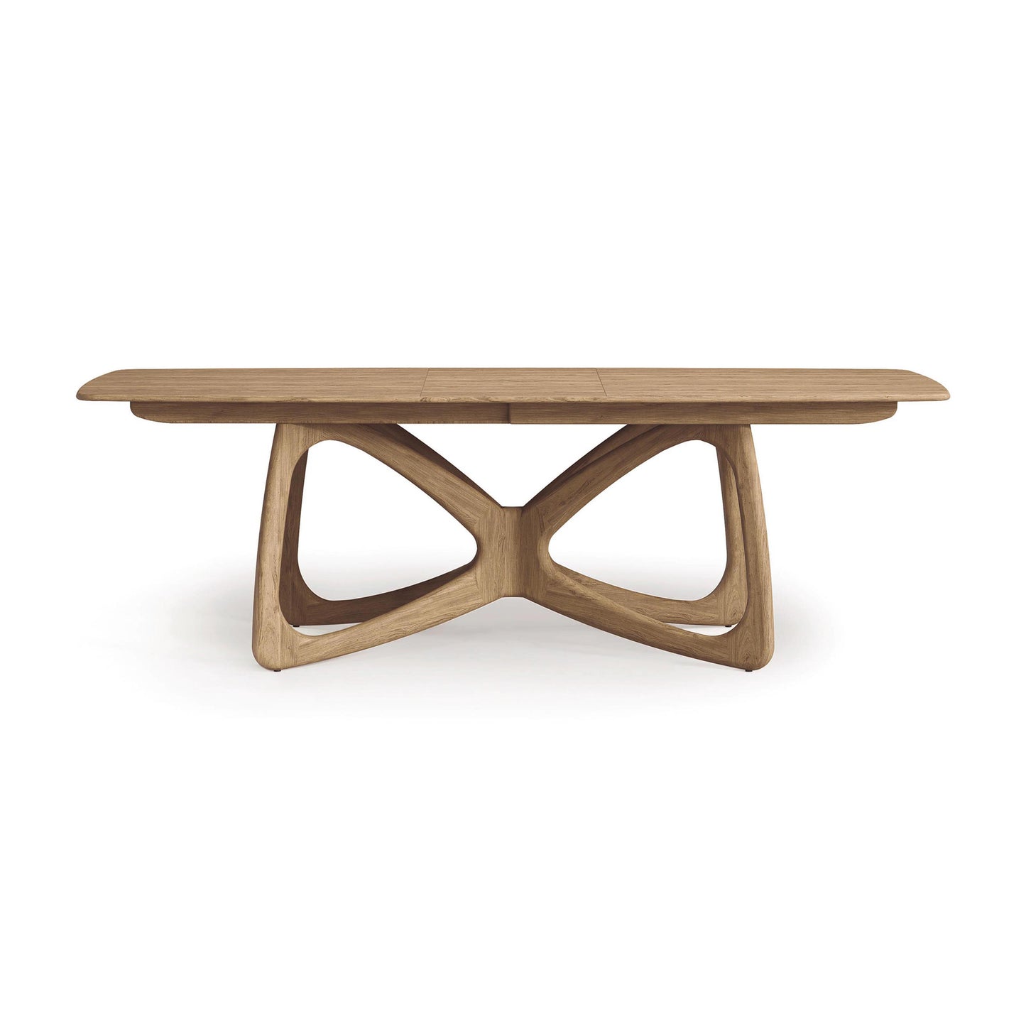 The Butterfly Extension Dining Table by Copeland Furniture features a distinct sculptural base comprised of elegantly curved, intersecting legs. Its smooth, rectangular tabletop is finished in a natural wood tone, crafted from sustainably sourced hardwoods, and epitomizes modern aesthetics alongside minimalist design.