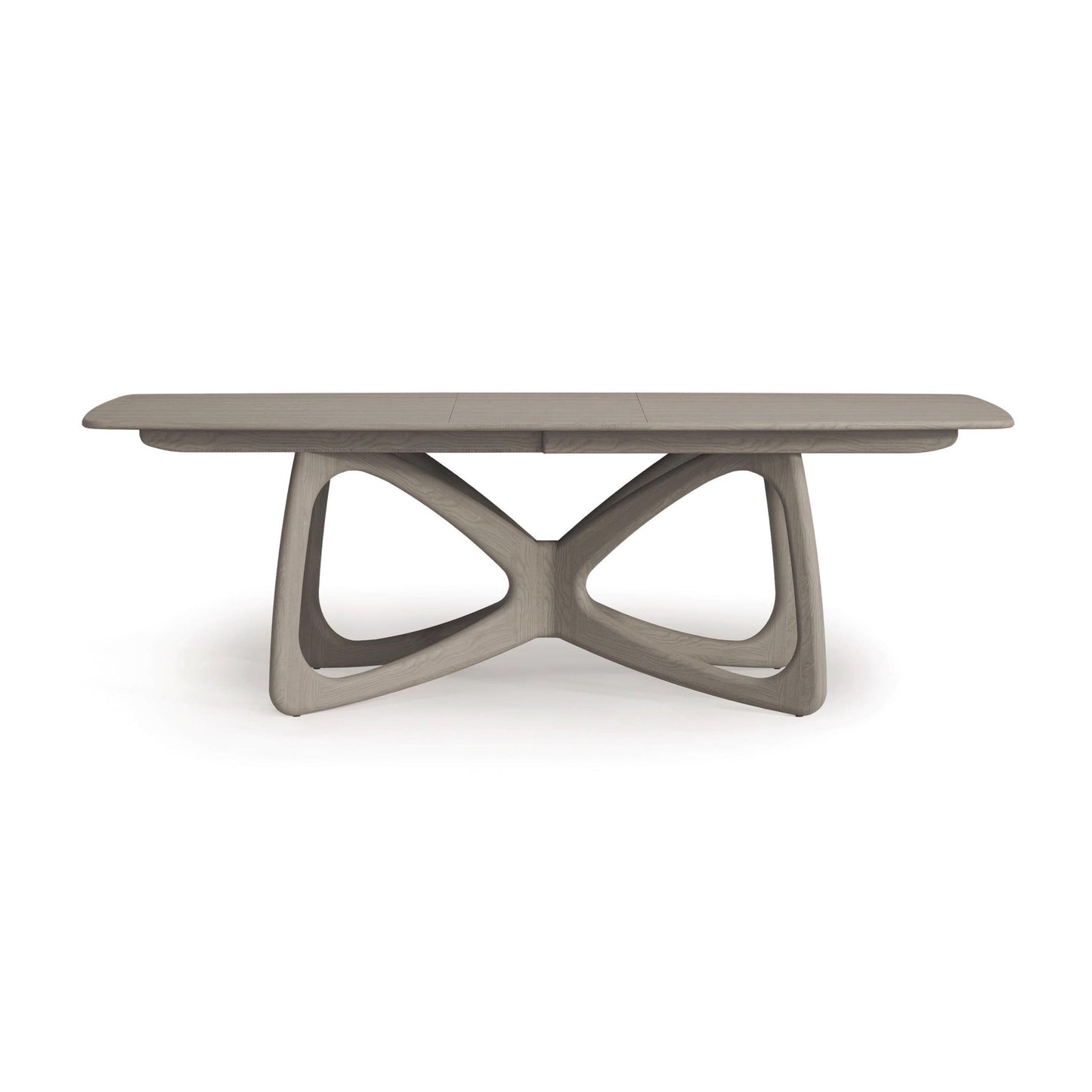 Copeland Furniture's Butterfly Extension Dining Table features a rectangular top and an artistic, curved base. Made from sustainably sourced hardwoods, it has a sleek light gray finish set against a white backdrop, epitomizing modern style.