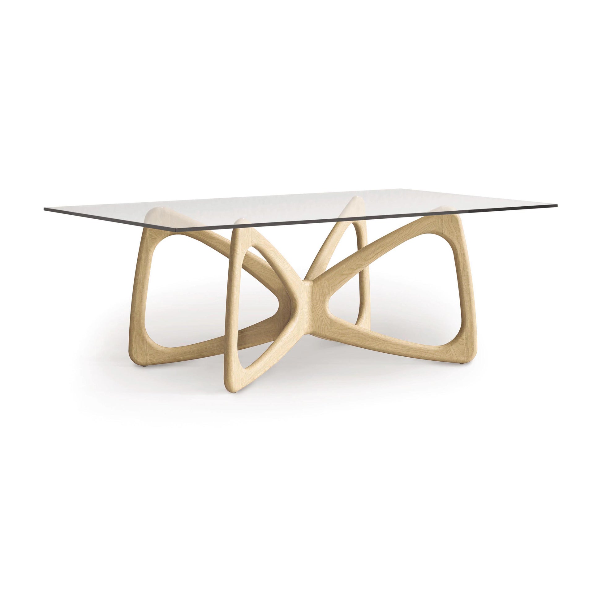 The Butterfly Glass Top Dining Table by Copeland Furniture features a modern design with a rectangular glass surface and a sculptural, geometric wooden base made from sustainably sourced hardwoods. Its interlocking, curved forms capture contemporary style, elegantly set against a plain white backdrop.