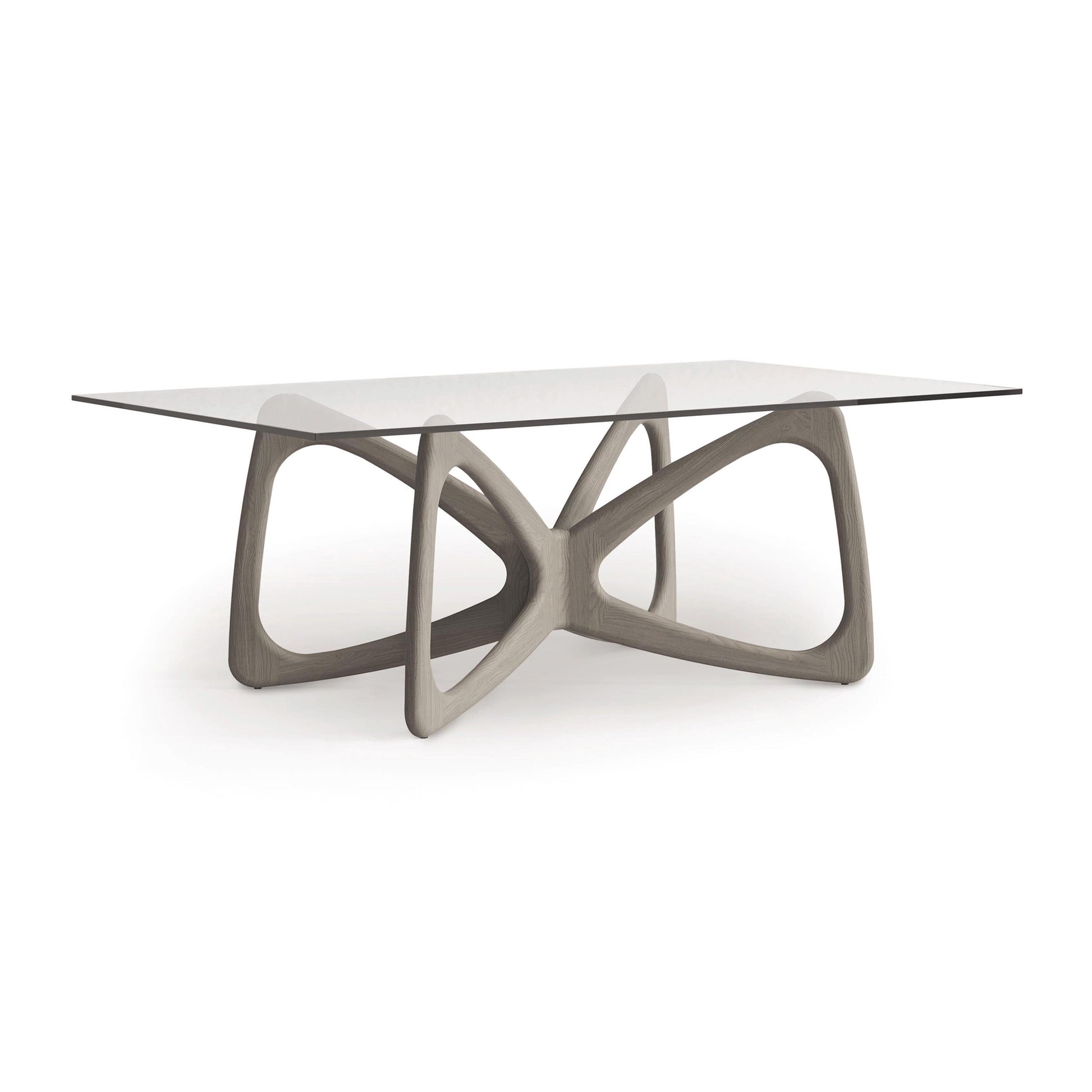 The Copeland Furniture Butterfly Glass Top Dining Table features a tempered glass surface and a uniquely designed wooden base with intersecting curves, crafted from sustainably sourced hardwoods, displayed on a simple white background.