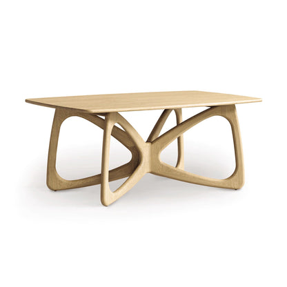 The Butterfly Solid Top Dining Table by Copeland Furniture is crafted from sustainably sourced hardwoods and features a rectangular top with an intricate, sculptural base made of interlocking, curved supports. Its natural finish highlights the grain against the plain white background, perfectly embodying modern aesthetics.