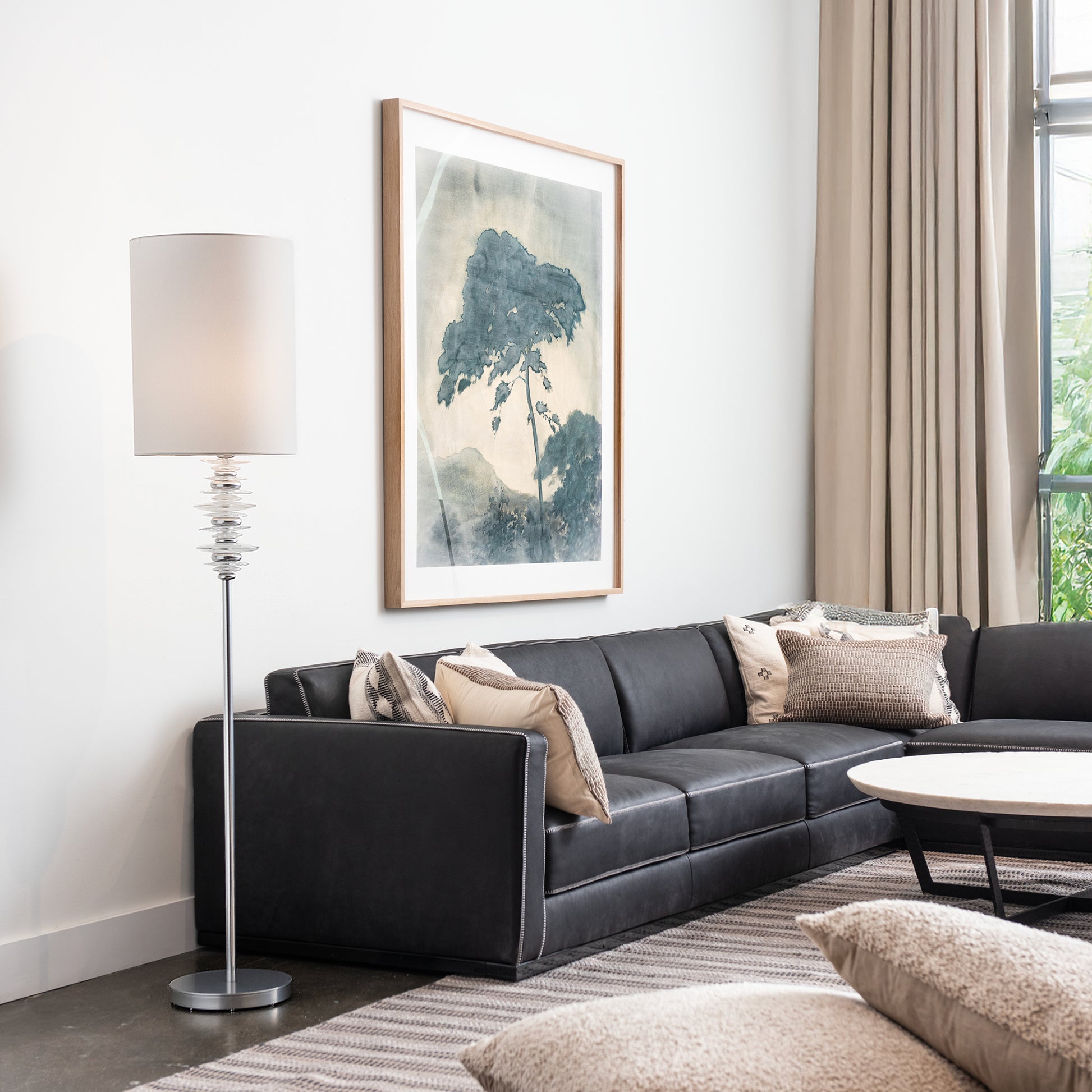 Black sectional sofa and round coffee table crafted in America, featuring quality design by Vermont Woods Studios, complemented by a Hubbardton Forge lamp.