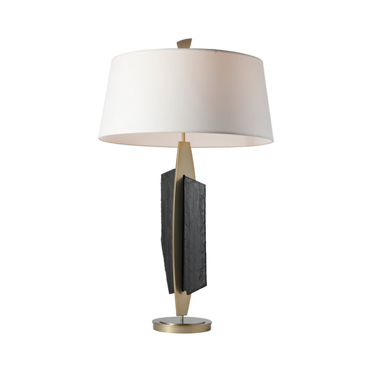 Cambrian Table Lamp by Hubbardton Forge featuring a white shade, gold base, and twin black slate accents on a central metal stem.