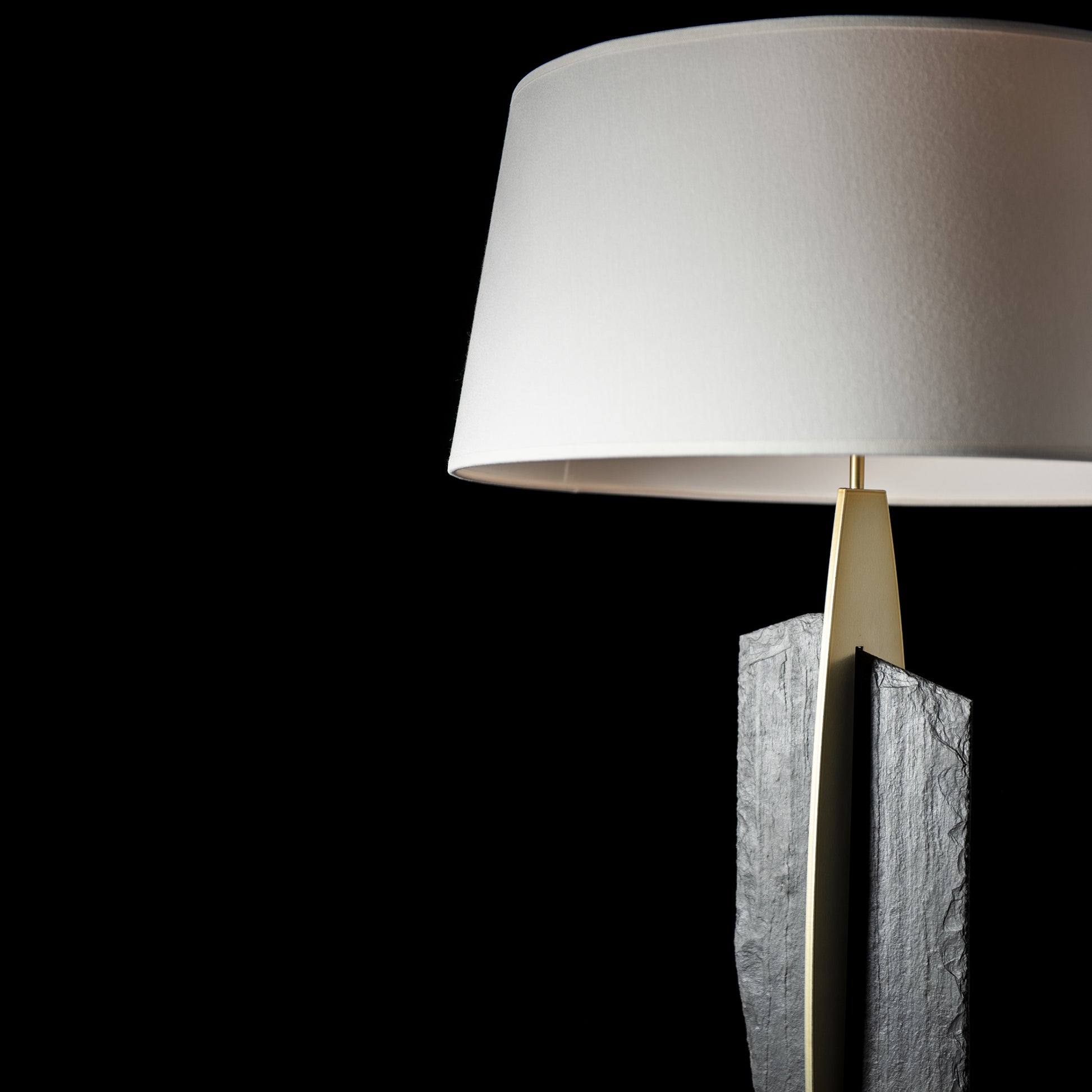 Cambrian Table Lamp by Hubbardton Forge, featuring a white lampshade and textured stone-like Vermont steel base, exemplifying modern elegance.