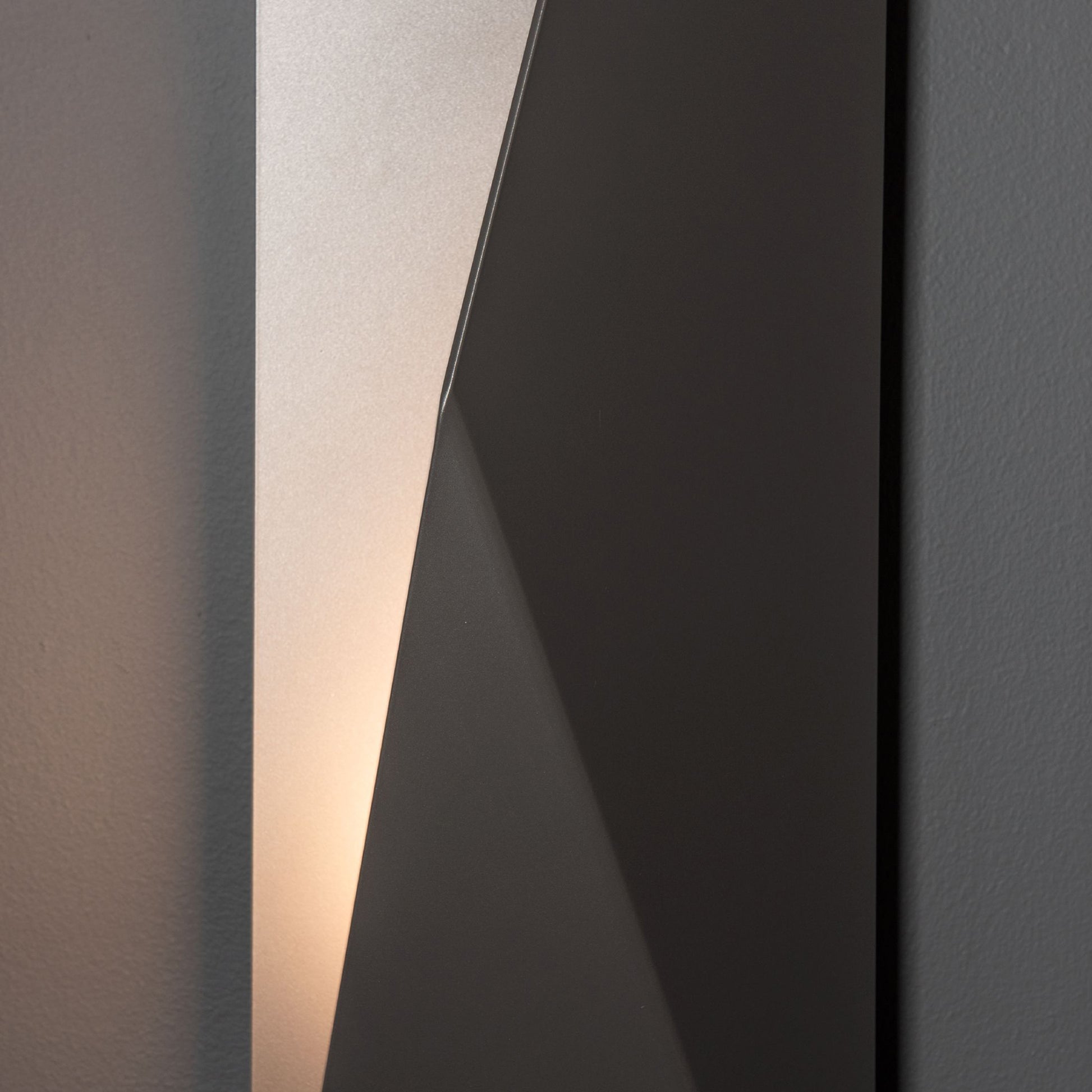 Hubbardton Forge Carbon Large Outdoor Sconce featuring angled panels and a modern design, showcased against a subtle gray background.