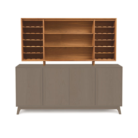 The Catalina 30" Buffet Hutch by Copeland Furniture features a mid-century modern design with four closed cabinets on the bottom and an open upper shelf unit. The upper section offers multiple small vertical shelves and a central open space. The bottom boasts a light gray color, while the top showcases a natural wood finish.