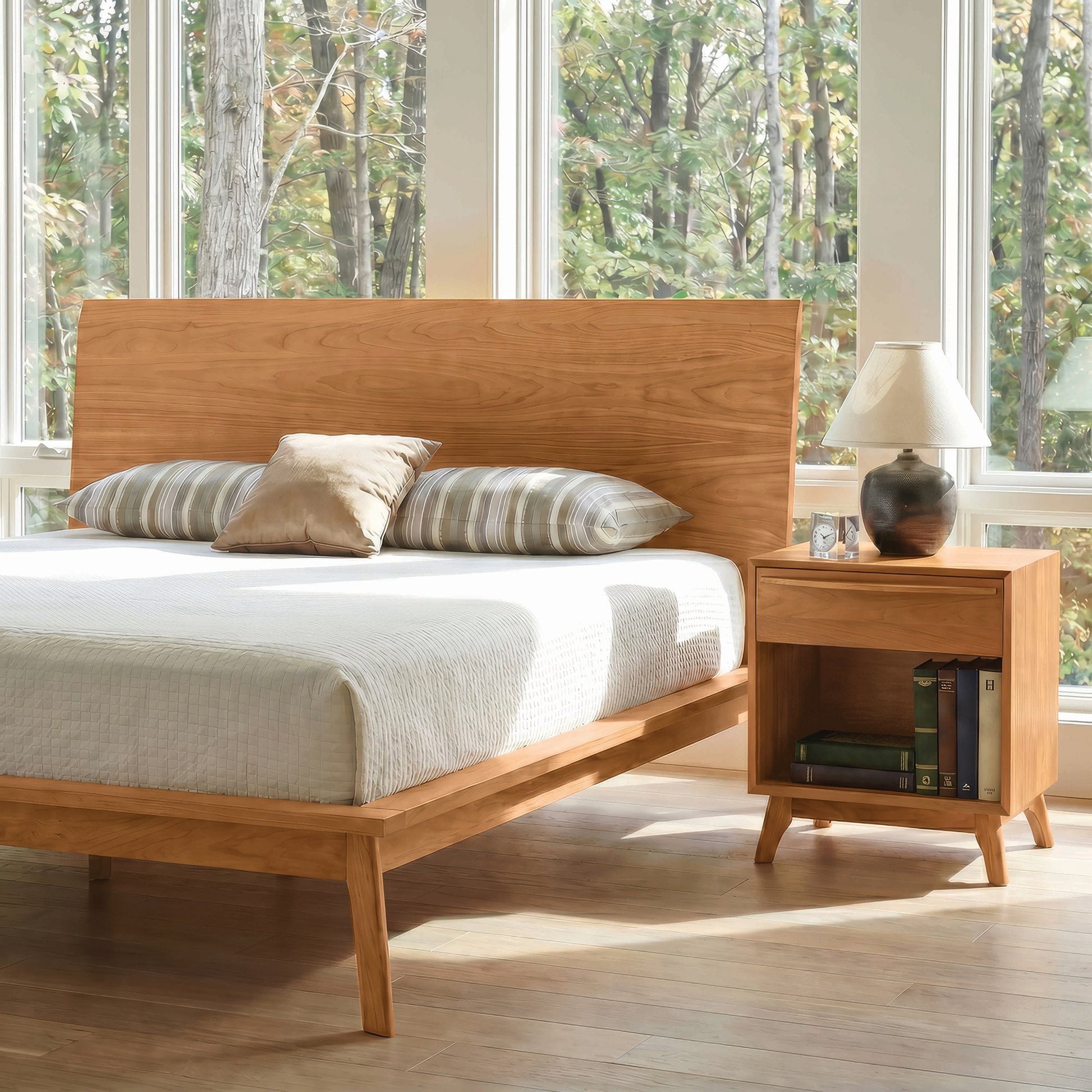 Copeland Furniture Catalina 1-Drawer Nightstand and wooden bed with striped pillows and beige blanket, showcasing fine American craftsmanship.