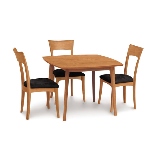 A Copeland Furniture Catalina Solid-Top dining table crafted from sustainably-sourced hardwoods, with four matching chairs that have black cushions, isolated on a white background.