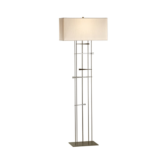 A Hubbardton Forge Cavaletti Floor Lamp with a beige shade featuring a geometric design.