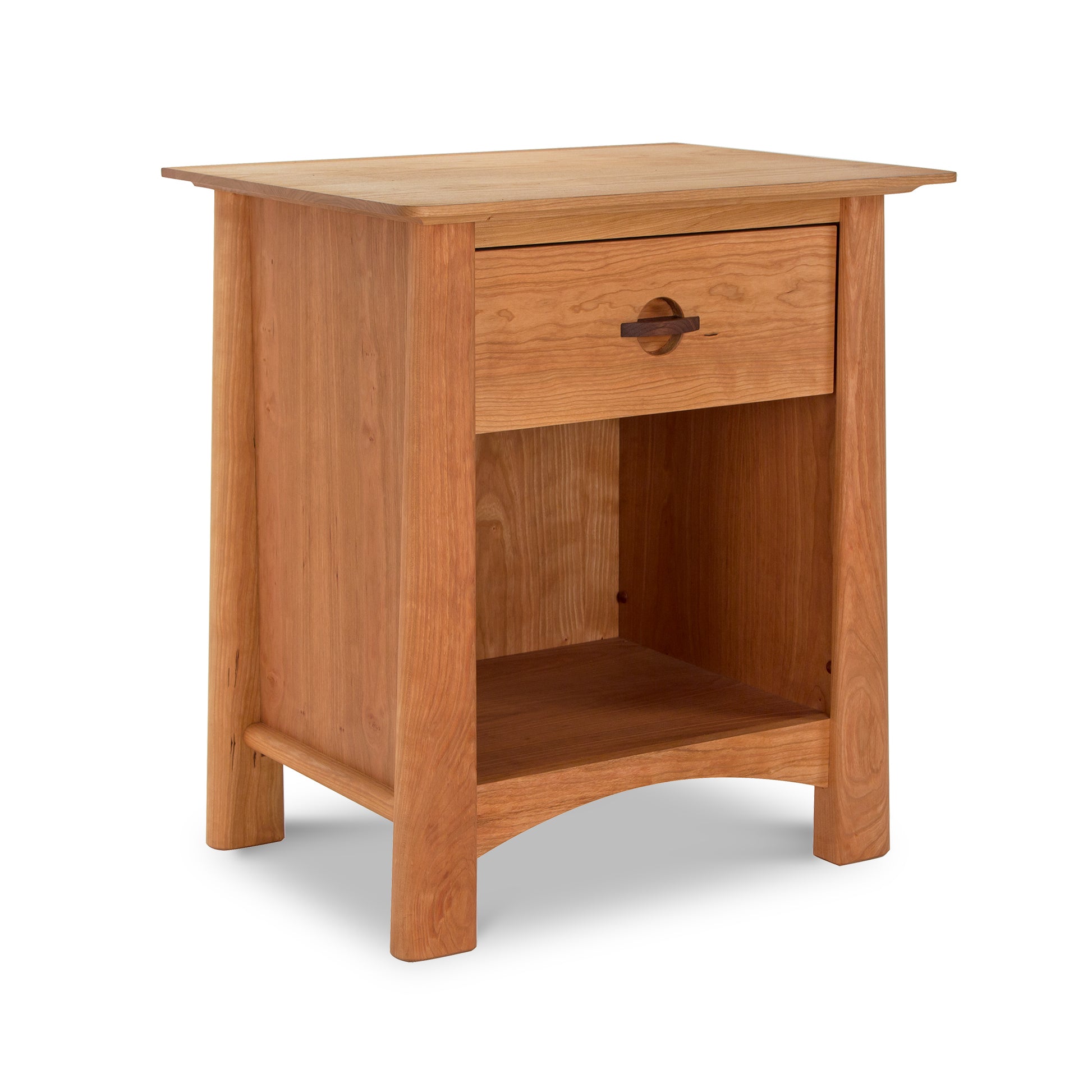 This wooden nightstand, finished in light brown, features a single drawer adorned with a round handle and an open storage area beneath. Its design boasts straight lines and slightly curved legs at the bottom, making it an ideal complement to sustainable bedroom furniture like the Cherry Moon 3-Piece Bedroom Set by Maple Corner Woodworks.