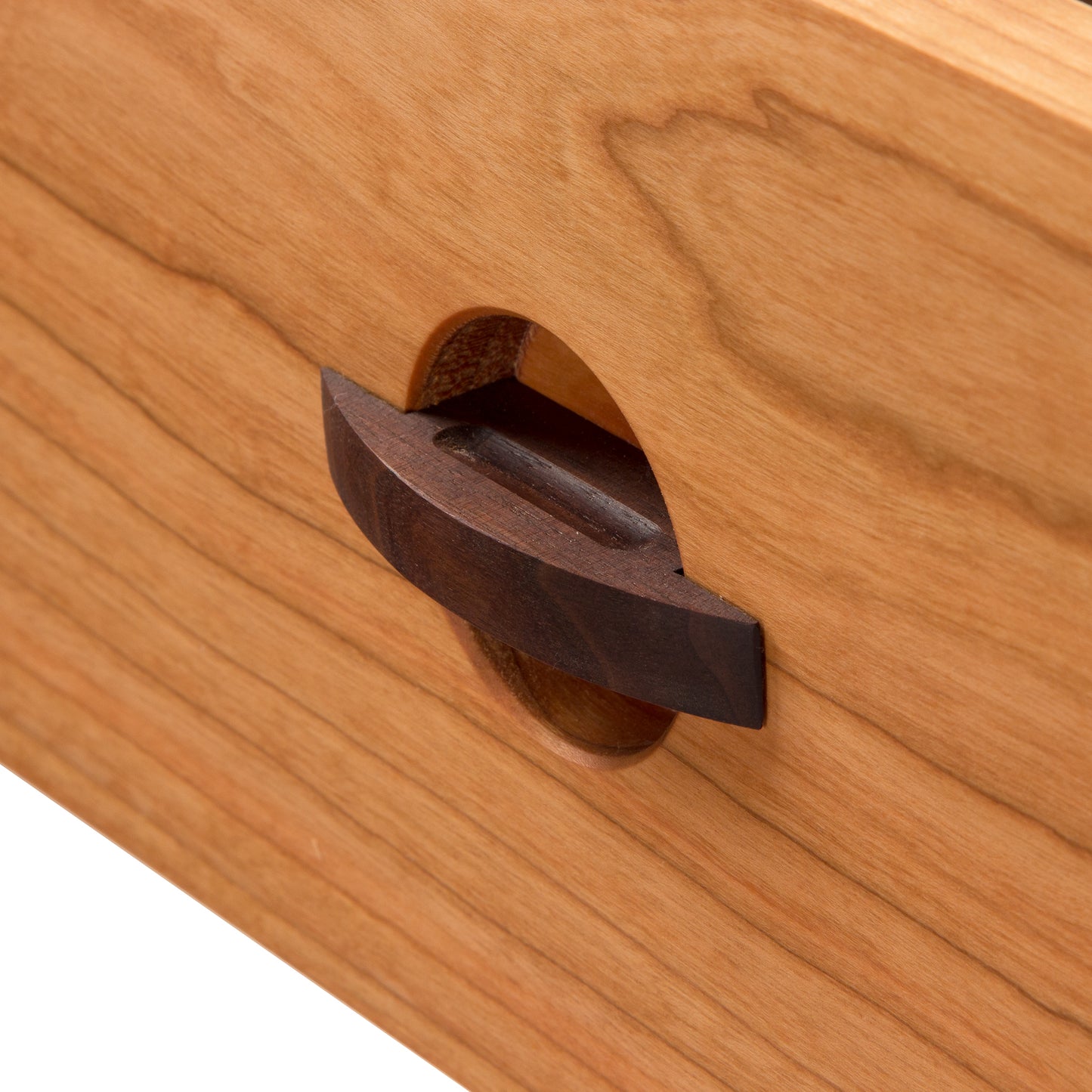 A close up of a Maple Corner Woodworks Cherry Moon 7-Drawer Dresser with a handmade wooden drawer and handle.